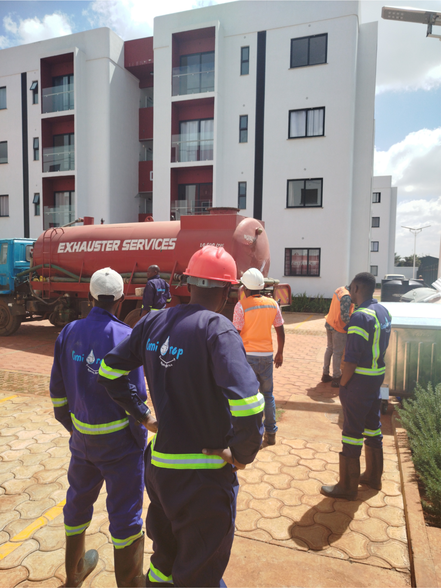 OmiDrop Africa exhauster truck emptying a residential septic tank at Tatu City, Nairobi — NEMA-licensed vacuum siphoning by a certified waste removal team