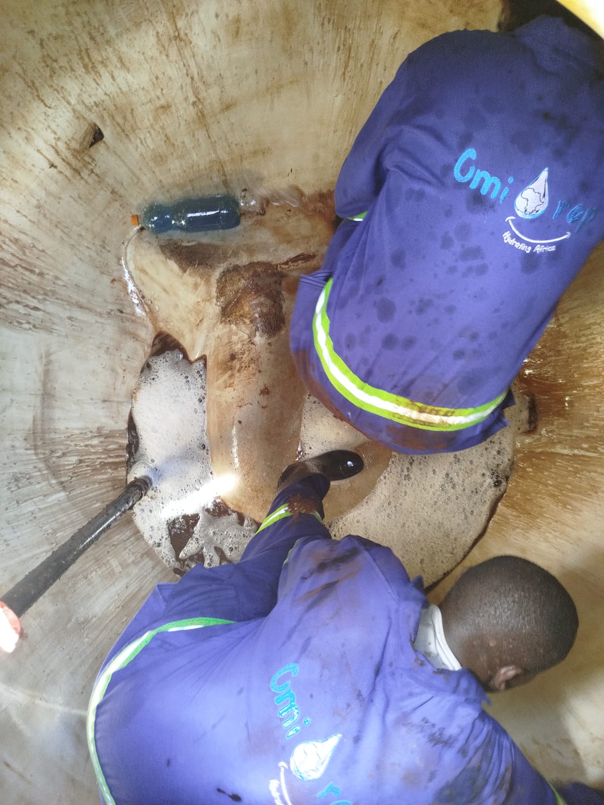 Omidrop Africa technician performing interior scrubbing inside a large concrete water tank in Nairobi, Kenya, during a professional water tank cleaning service